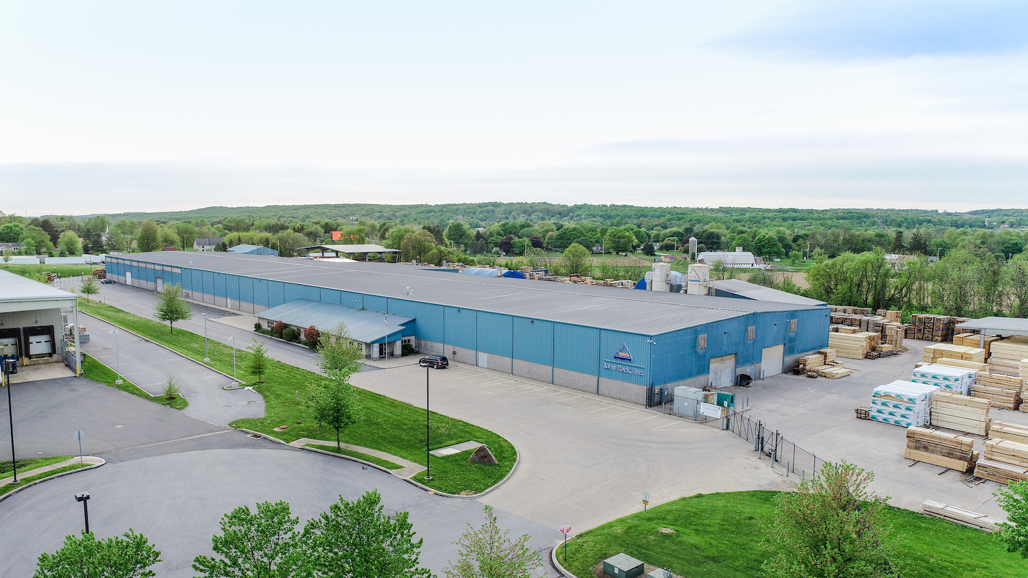 Aerial view of blue industrial building showcasing entrance and side yard.